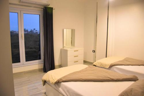 a bedroom with two beds and a window at Quiet Corner Apartment in Luxor