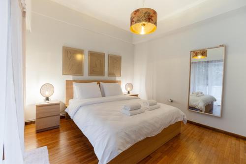 een witte slaapkamer met een groot bed en een spiegel bij Daphnes Home Chalkida Central in Chalkida