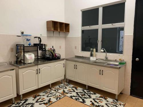 una cucina con mobili bianchi, un lavandino e una finestra di F'Seven Homestay a Bedung