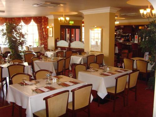 a dining room with white tables and chairs at Villa Hotel in Hamilton