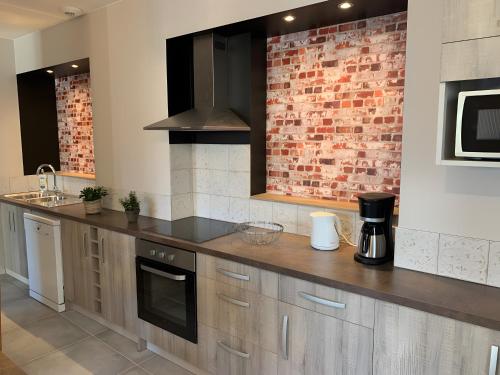 een keuken met een aanrecht en een bakstenen muur bij Gîte Un Toit Pour Vous in Les Épesses