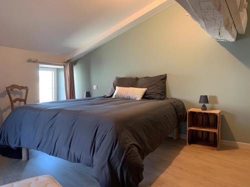 een slaapkamer met een bed met een blauw dekbed bij Gîte Un Toit Pour Vous in Les Épesses