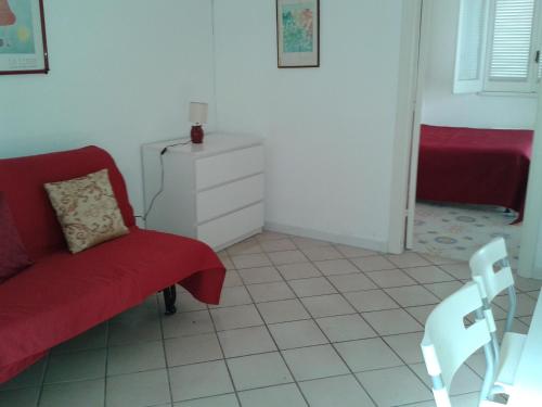 a living room with a red couch and a chair at Pitosforo - Ulivo - Cocco in Ischia