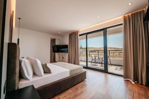 een slaapkamer met een bed en een groot raam bij Cuni Luxury Hotel in Sarandë