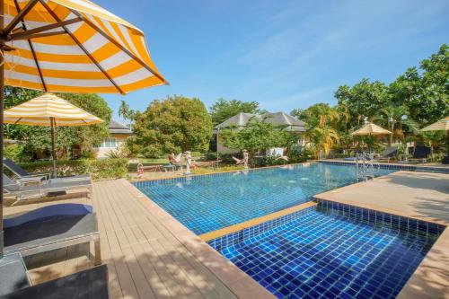 a swimming pool with an umbrella and people swimming at Perennial Resort in Nai Yang Beach