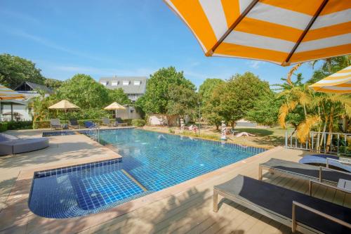 a swimming pool with chairs and an umbrella at Perennial Resort in Nai Yang Beach
