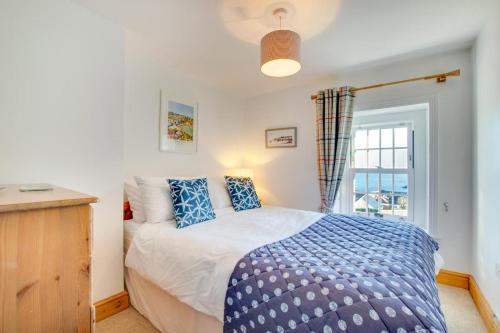 ein Schlafzimmer mit einem Bett mit blauen Kissen und einem Fenster in der Unterkunft 3 Bed in Gorran Haven oc-p00812 in Gorran Haven