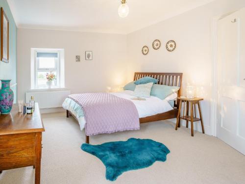 een slaapkamer met een bed en een blauw tapijt bij 3 Bed in Narberth 79443 in Narberth