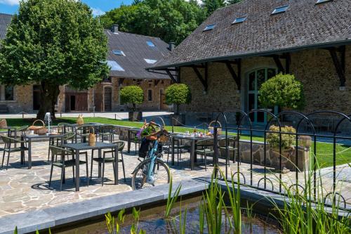 Ein Fahrrad, das neben einer Terrasse mit Tischen und Stühlen geparkt ist. in der Unterkunft Auberge du chateau de Leignon in Leignon
