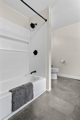 a white bathroom with a tub and a toilet at NEW HOT TUB Game Room Firepit Near Windham in Prattsville