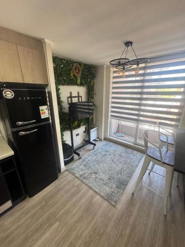 een woonkamer met een zwarte koelkast en een tafel bij Estacionamiento, Céntrico y Cómodo in Chillán