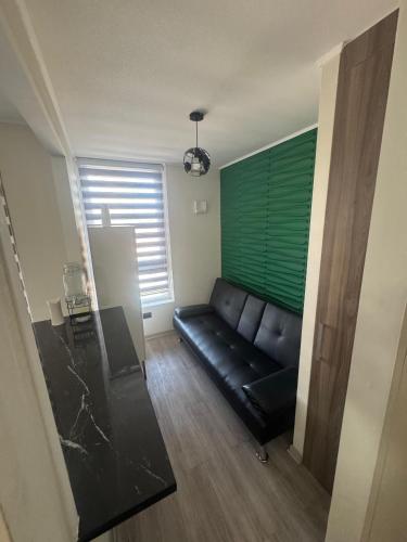 een zwarte bank in een woonkamer met een groene muur bij Estacionamiento, Céntrico y Cómodo in Chillán