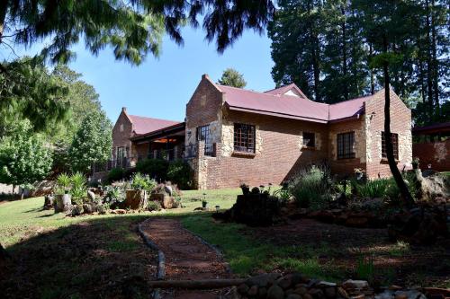 an old brick house with a pathway in front of it at Rawlingsons Country House in Dullstroom