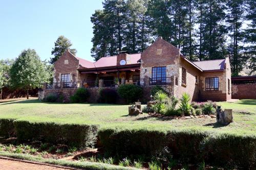 a large brick house on a grassy yard at Rawlingsons Country House in Dullstroom