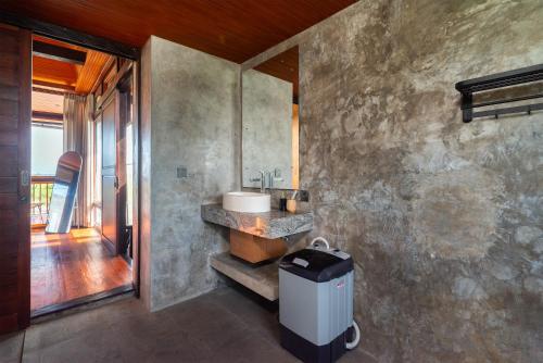 een badkamer met een wastafel en een betonnen muur bij Villa Taru Jagat in Saba