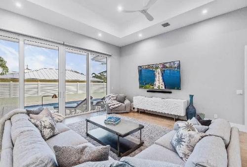 ein Wohnzimmer mit Sofa und Fernseher in der Unterkunft Spacious Three Bedroom Lakeside Home with Relaxed Coastal Comfort in Palm Beach Shores