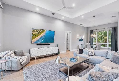 ein Wohnzimmer mit einem Sofa und einem Fernseher an der Wand in der Unterkunft Spacious Three Bedroom Lakeside Home with Relaxed Coastal Comfort in Palm Beach Shores