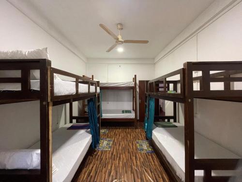 une chambre avec trois lits superposés et un ventilateur de plafond dans l'établissement Femingo by Costels, à Hiriketiya
