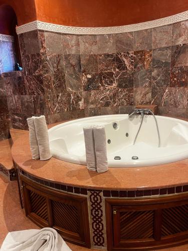a bath tub in a bathroom with a stone wall at Villa Oum Palace in Marrakesh