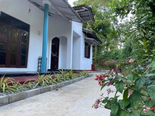 une maison blanche avec une porte et quelques fleurs dans l'établissement Femingo by Costels, à Hiriketiya