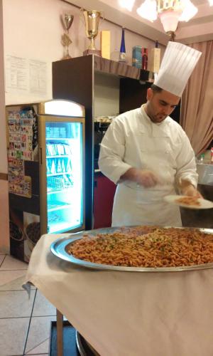 a chef preparing a large pizza in a kitchen at Hotel Degli Amici in Sant'Egidio del Monte Albino
