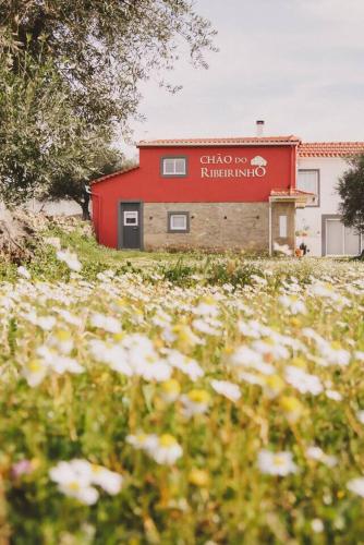 a red building with a sign on the side of it at Chão do Ribeirinho Country House in Atalaia