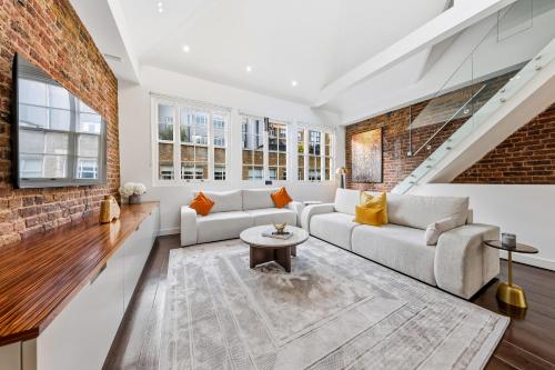 a living room with white furniture and a brick wall at The Marylebone Villa in London
