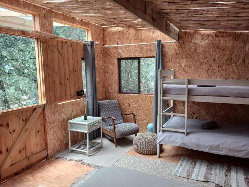 een kamer met 2 stapelbedden en een stoel bij Gaia River Cabin in Swellendam