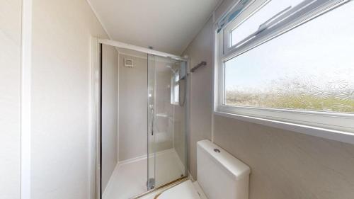 a bathroom with a shower and a toilet and a window at C37 Jupiter, Riviere Towans in Hayle