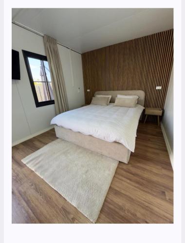 a bedroom with a large bed with white sheets at הבקתות של מאי in Ẕomeẖa