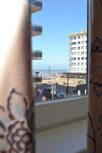 a window with a view of a beach and a building at Het Koetshuis, op 50m van zee, voor 5 personen, centrum Westende BAD, alle comfort in Middelkerke