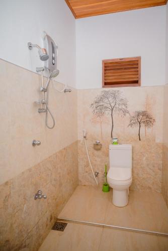 a bathroom with a toilet and a shower with trees on the wall at Shehani Beach Bungalow in Tangalle