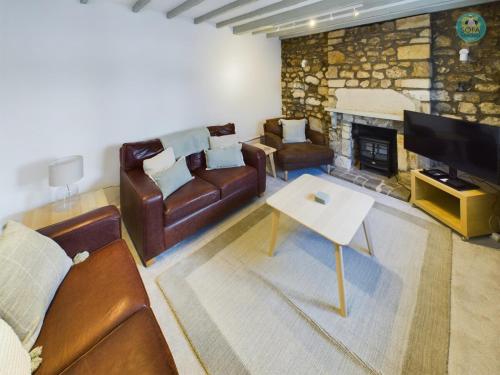 een woonkamer met lederen meubels en een open haard bij Sea Salt - Beer, East Devon in Beer
