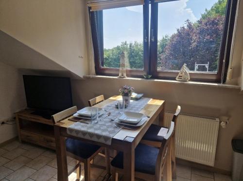 een eetkamer met een tafel met stoelen en een raam bij Ferienwohnung Thomée in Looft