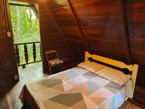 una camera da letto con un letto in una stanza con una finestra di Chalé Floresta Amada a Ouro Preto