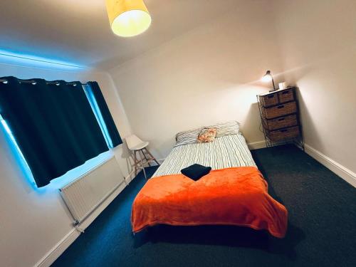 a bedroom with a bed with an orange blanket at Pebbles Guest House - Flat 5 in Southampton