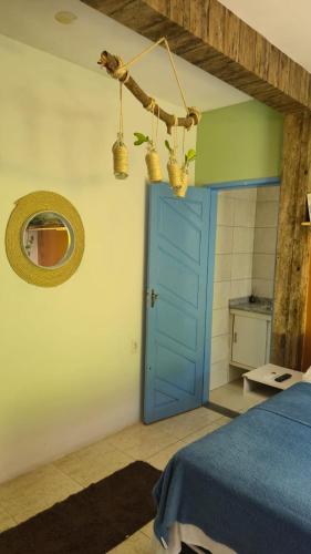 a bedroom with a blue door and a mirror at Pousada Caribe in Itacimirim