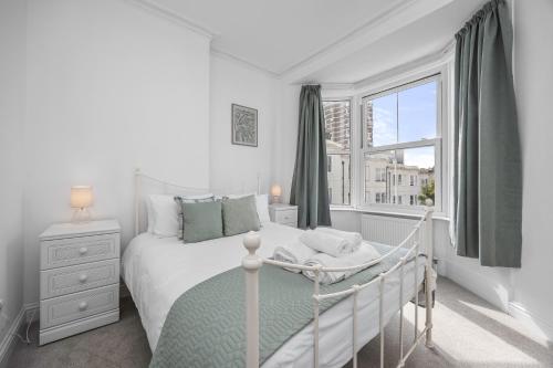 a white bedroom with a bed and a window at Spacious 2 Bed & 1 Bath - Close to Beach & City Centre in Brighton & Hove