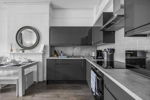a kitchen with black cabinets and a sink at Spacious 2 Bed & 1 Bath - Close to Beach & City Centre in Brighton & Hove
