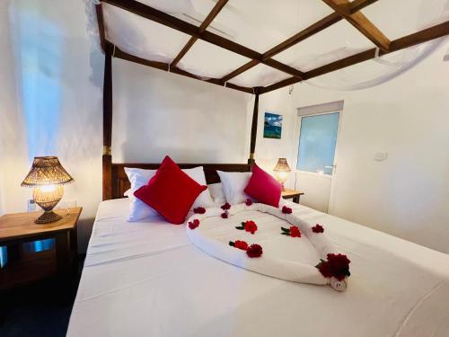 a bedroom with a white bed with red flowers on it at Sunburst Villa in Tangalle