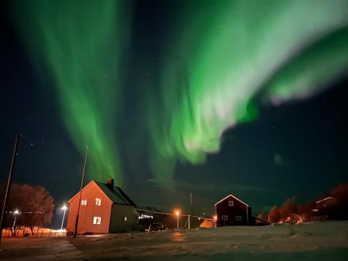 un'immagine dell'aurora nel cielo sopra le case di Mikkelsby house by Altafjord ad Alta