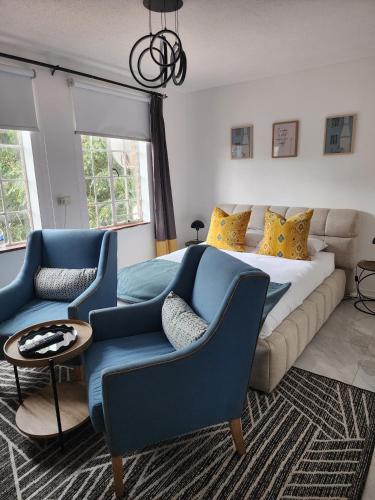 Un dormitorio con una cama y dos sillas azules. en Lanina Harare Avenues Apartment, en Harare