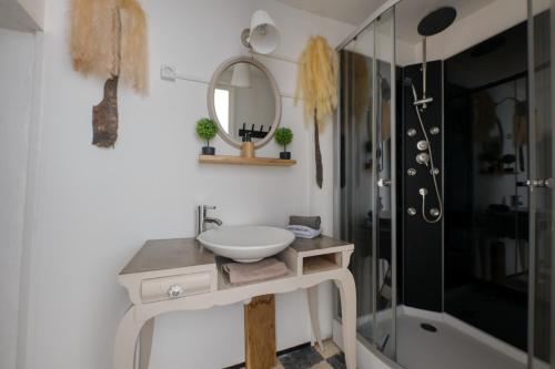 Un baño con lavabo, espejo y ducha. en Les Terrasses de Choubaka, en Alignan-du-Vent