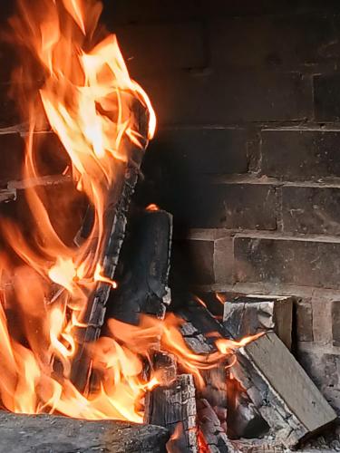 a fire in a brick oven with flames at Ceira Cottage - Refúgio Romântico com Vista Serrana in Góis