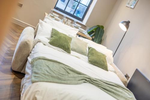 a large bed with green pillows in a room at Leeds City Luxe Apartment with Parking, 8 mins to station! in Central Station