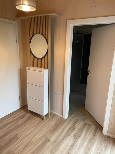 ein leeres Zimmer mit einer Kommode und einem Spiegel in der Unterkunft Moderne Maisonette-Ferienwohnung mit Dachterrasse, Waldblick & Parkplatz in Friedburg
