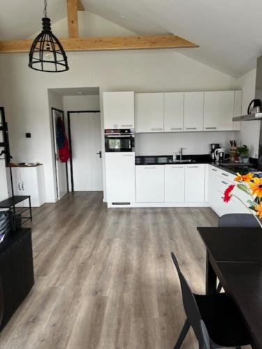 a kitchen with white cabinets and a wooden floor at Lauwershuisje, Sauna, Harbour Lauwersmeer in Anjum