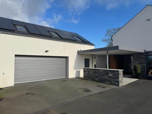 a white house with a garage with a solar roof at The Loft in Lurgan