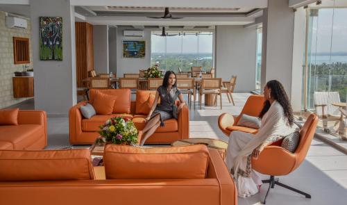 Zwei Frauen sitzen auf orangefarbenen Stühlen in einer Lobby in der Unterkunft Blue Ocean Resort & Residences in Zanzibar City