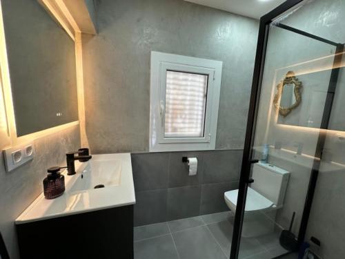 Un baño con lavabo, inodoro y ducha. en Preciosa casa con piscina desbordante y vistas al mar, en Roses